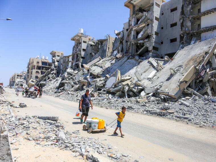 Familias caminan en medio de la destrucción en la Franja de Gaza tras la serie de ataques militares de Israel en contra del territorio de Palestina.