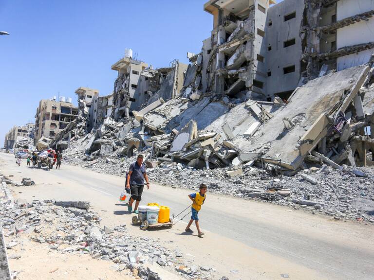 Familias caminan en medio de la destrucción en la Franja de Gaza tras la serie de ataques militares de Israel en contra del territorio de Palestina.
