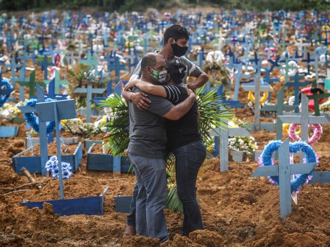 Familiares de una víctima del covid-19 lloran en un cementerio de Brasil