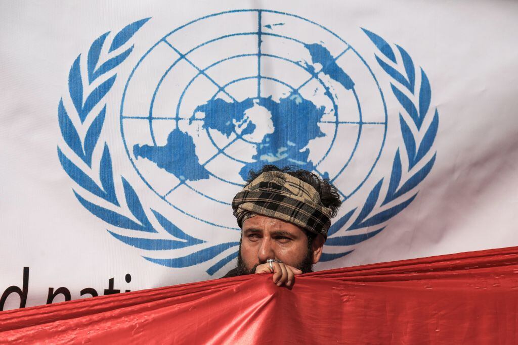 Hombre con la bandera de Irak adelante del logo de las Naciones Unidas