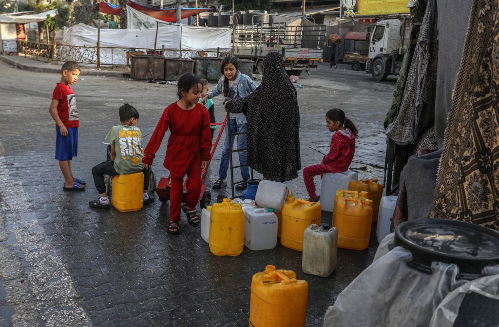 Un grupo de niños palestinos se acercan a buscar bidones con agua en la zona de Rafah en el sur de la Franja de Gaza.