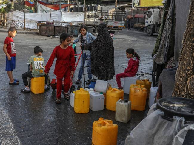 Un grupo de niños palestinos se acercan a buscar bidones con agua en la zona de Rafah en el sur de la Franja de Gaza.