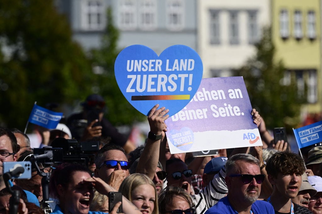 Seguidores de la ultraderecha en Alemania con un cartel "nuestro país primero" del partido AfD en un acto de campaña en el estado de Turingia.