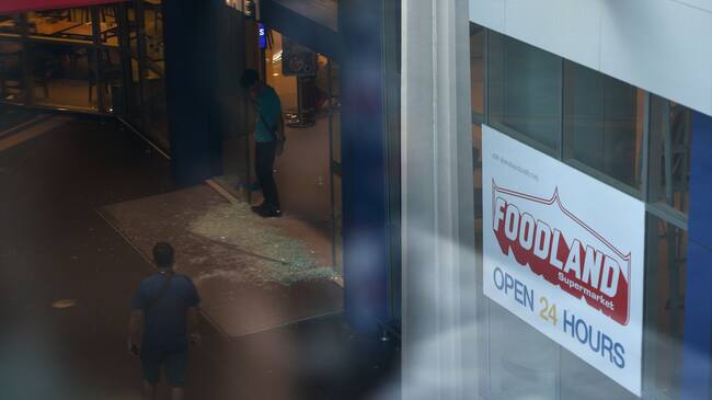 People look at smashed glass on the floor next to the entrance of the Terminal 21 shopping mall following a mass shooting in Nakhon Ratchasima on February 9, 2020. - A Thai soldier who killed at least 26 people before being shot dead in a mall by commandos went on the rampage because of a debt dispute, the kingdom's premier said on February 9, offering the first official speculation for the motive of an "unprecedented" shooting spree. (Photo by CHALINEE THIRASUPA / AFP) (Photo by CHALINEE THIRASUPA/AFP via Getty Images)