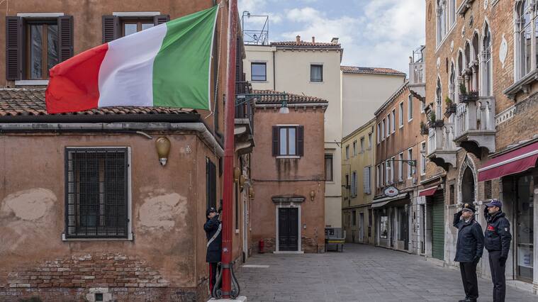 VENICE, ITALY - MARCH 31: Carabinieri raise the flag at half-mast to remember people dying of corona virus on March 31, 2020 in Venice, Italy. The Italian government continues to enforce the nationwide lockdown measures to control the spread of COVID-19. (Photo by Stefano Mazzola/Awakening/Getty Images)