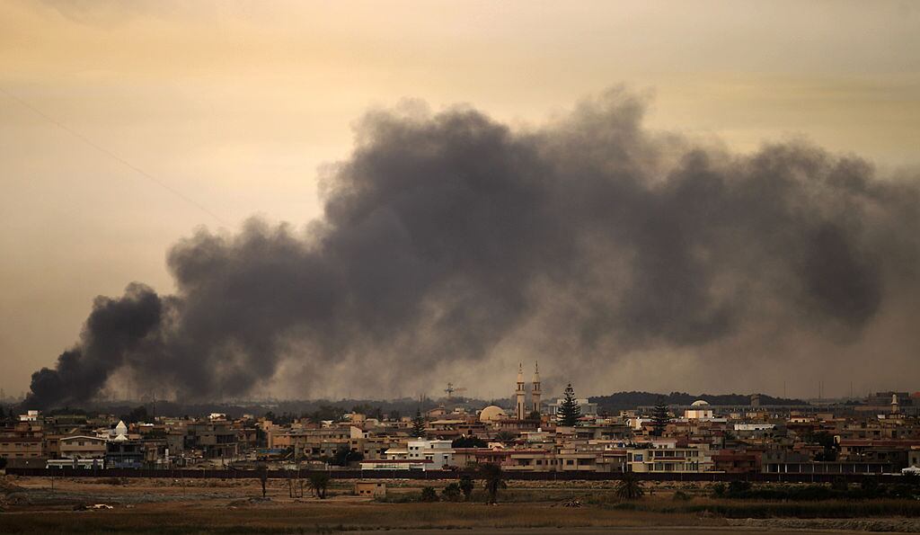 Una ciudad de Libia ve como el humo se levanta tras un impacto de un proyectil.