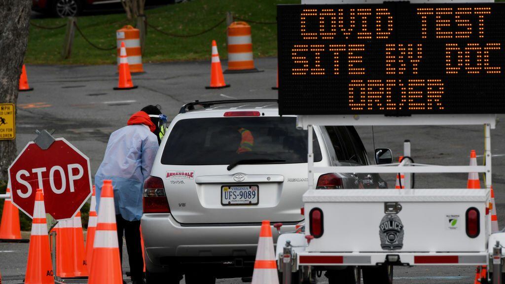 A healthcare worker oversees cars as people arrive to get tested for a Covid-19 test, at a testing site in Arlington, Virginia on December 1, 2020. (Photo by Olivier DOULIERY / AFP) (Photo by OLIVIER DOULIERY/AFP via Getty Images)