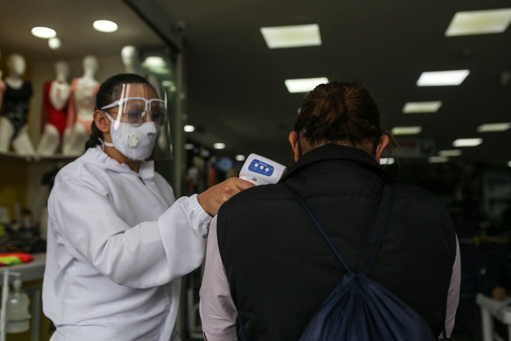 Trabajadores toman la temperatura en un local de Bogotá