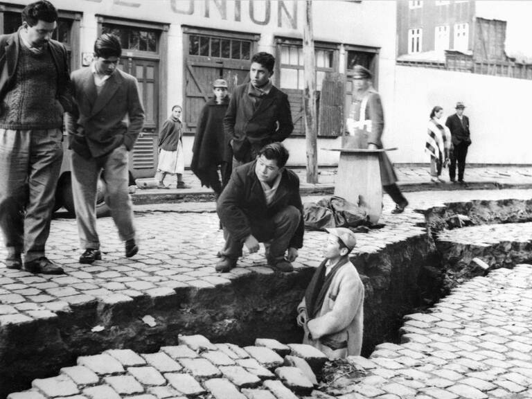 picture taken in April 1960 in Valdivia of people looking at an enormous crack on a street due to the earthquake that struck the area on May 22, 1960. AFP PHOTO (Photo credit should read STF/AFP via Getty Images)