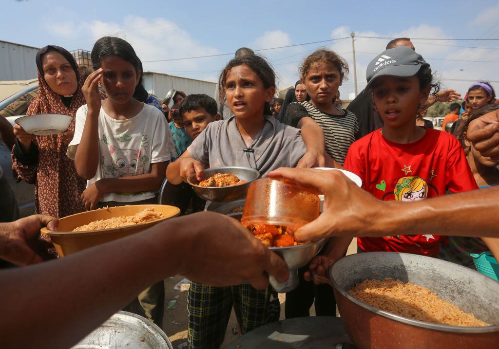 Un grupo de niños palestino recibe una porción de alimentos en la Franja de Gaza en Palestina, en medio de los ataques militares de Israel.