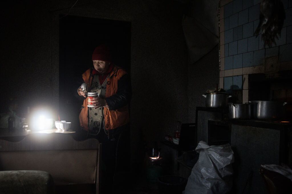 Mujer se ilumina con una lámpara por la falta de electricidad en Jersón
