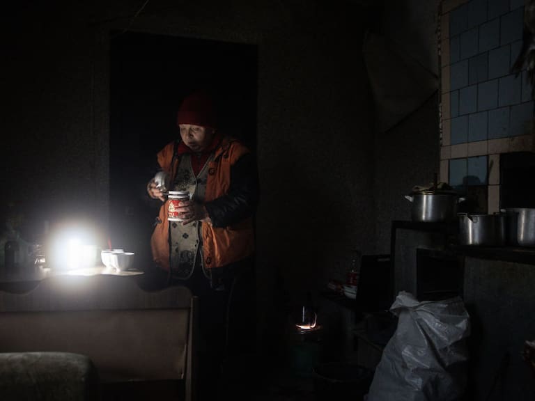 Mujer se ilumina con una lámpara por la falta de electricidad en Jersón