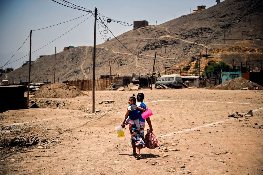 Una mujer lleva a su hijo por las calles de tierra en Perú