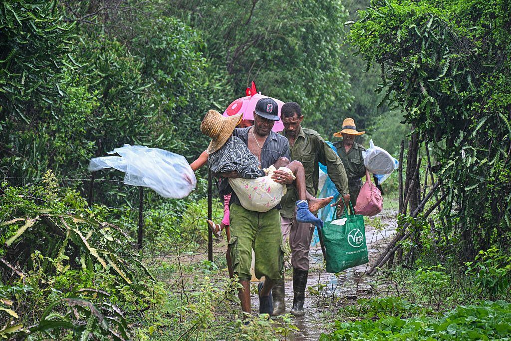 TOPSHOT - Residents self-evacuate under pouring rain from Playa Siboney to safe locations ahead of the arrival of Hurricane Melissa, in Santiago de Cuba, Cuba, on October 28, 2025. Hurricane Melissa was set to strike nearby eastern end of Cuba late Tuesday after pummeling Jamaica. (Photo by YAMIL LAGE / AFP) (Photo by YAMIL LAGE/AFP via Getty Images)