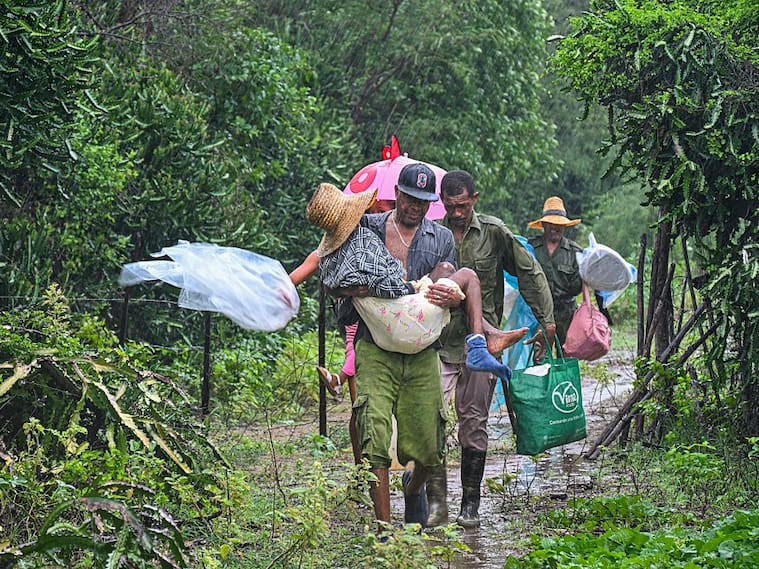 TOPSHOT - Residents self-evacuate under pouring rain from Playa Siboney to safe locations ahead of the arrival of Hurricane Melissa, in Santiago de Cuba, Cuba, on October 28, 2025. Hurricane Melissa was set to strike nearby eastern end of Cuba late Tuesday after pummeling Jamaica. (Photo by YAMIL LAGE / AFP) (Photo by YAMIL LAGE/AFP via Getty Images)