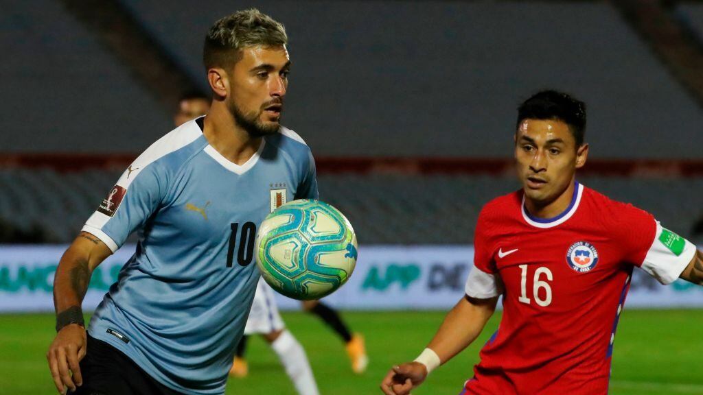 Uruguay's Giorgian De Arrascaeta (L) is challenged by Chile's Claudio Baeza during their 2022 FIFA World Cup South American qualifier football match at the Centenario Stadium in Montevideo on October 8, 2020, amid the COVID-19 novel coronavirus pandemic. (Photo by Raul MARTINEZ / POOL / AFP) (Photo by RAUL MARTINEZ/POOL/AFP via Getty Images)