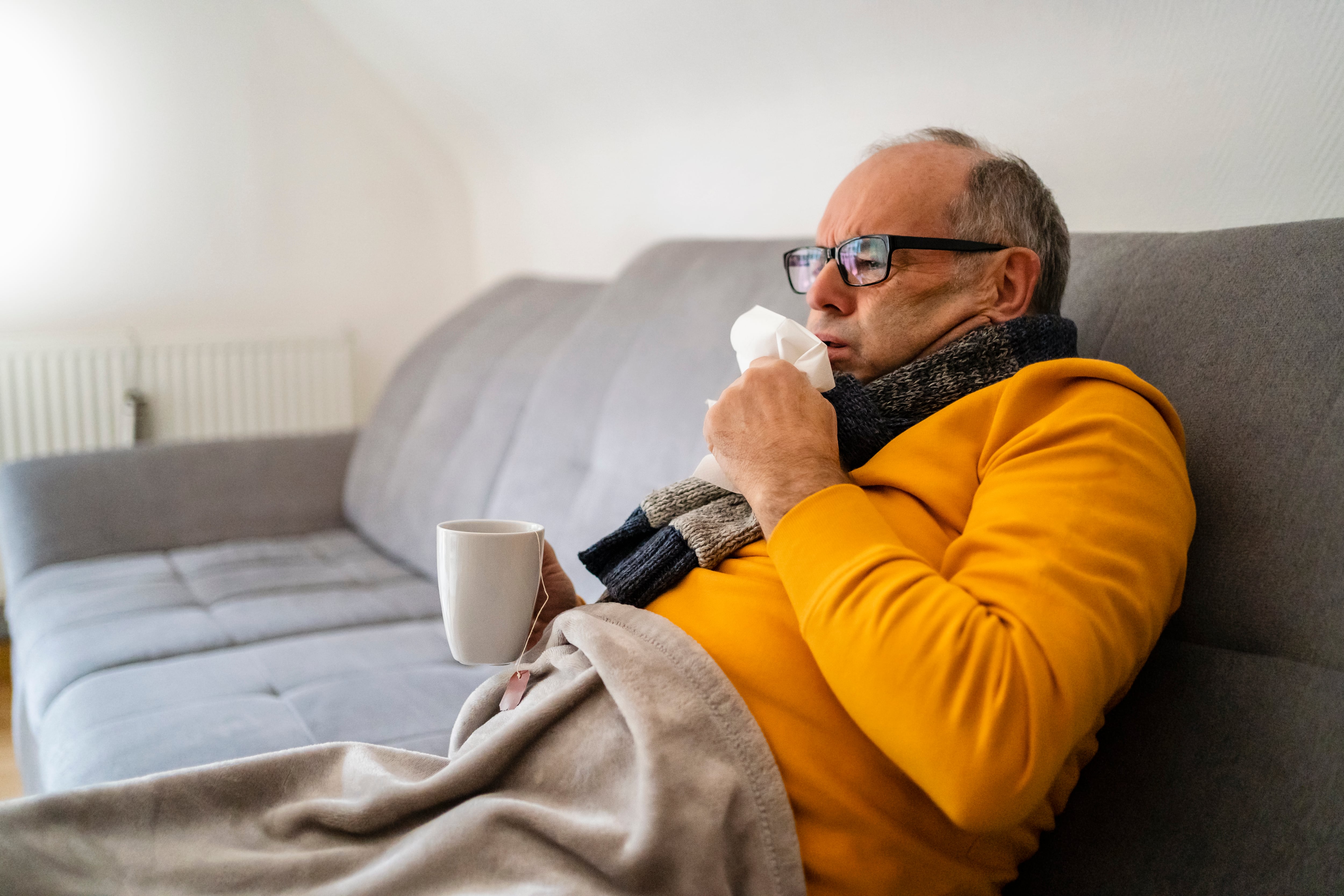 Man coughing sitting on sofa in living room