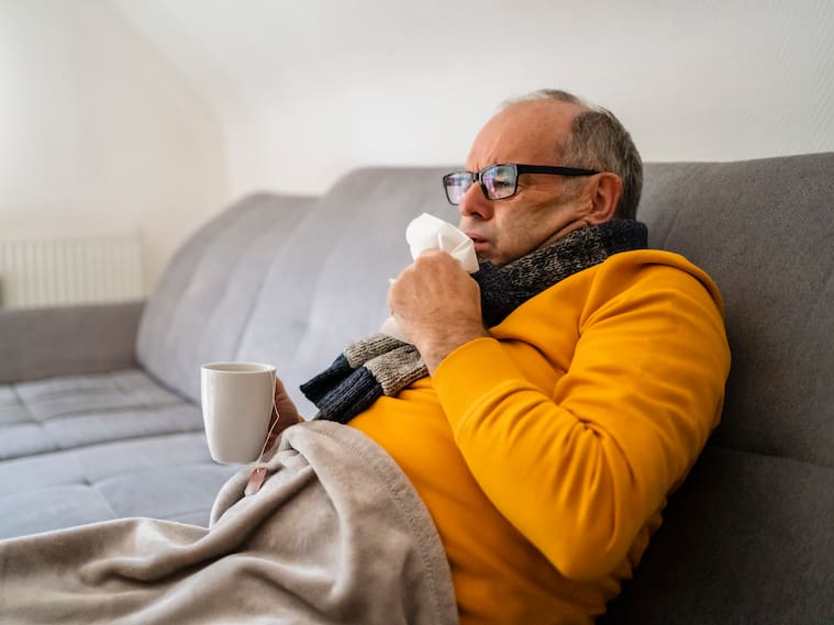 Man coughing sitting on sofa in living room