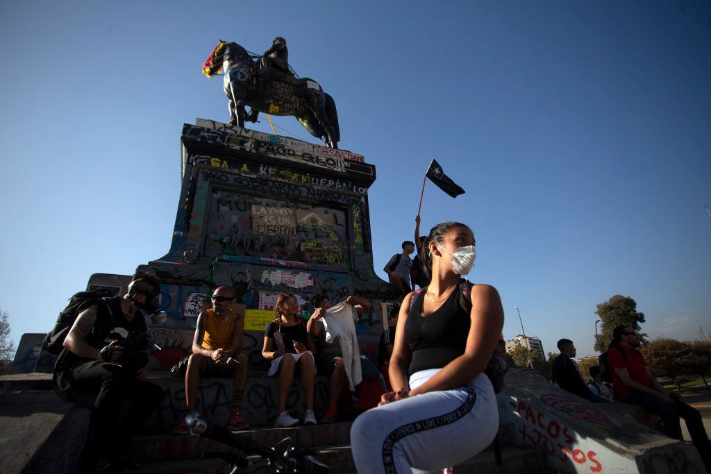 TOPSHOT - A demonstrator wears a face mask as a precautionary measure against the spread of the new coronavirus, COVID-19, during a protest -with little participation- against Chilean President Sebastian Pinera's government in Santiago on March 16, 2020. - Chile announced a total closure of its borders on Monday while LATAM (Latin America's largest airline) said it was reducing operations by 70 percent as the region scrambled to stem the rapidly-spreading coronavirus pandemic. (Photo by CLAUDIO REYES / AFP) (Photo by CLAUDIO REYES/AFP via Getty Images)