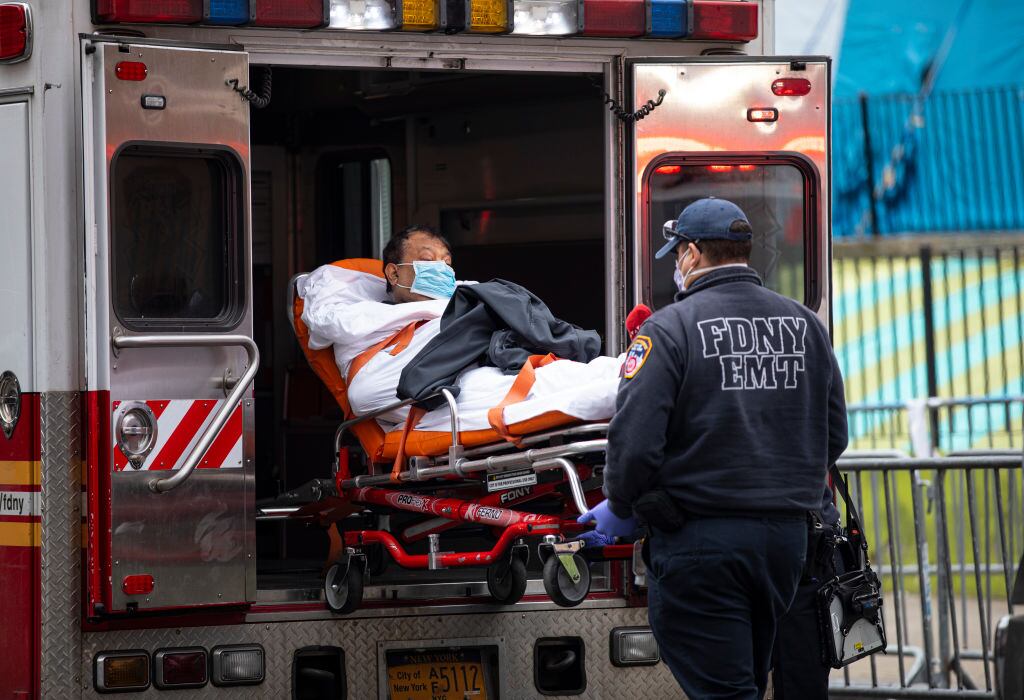 QUEENS, NEW YORK - MARCH 30: Two members of the Fire Department of New York"u2019s Emergency Medical Team wheel in a patient with potentially fatal coronavirus to the Elmhurst Hospital Center in the Queens borough of New York City on March 30, 2020. New York City is the epicenter of the coronavirus pandemic in the United States, putting historic pressure on a world-renowned healthcare system as the number of confirmed cases in the area grows. (Photo by Robert Nickelsberg/Getty Images)