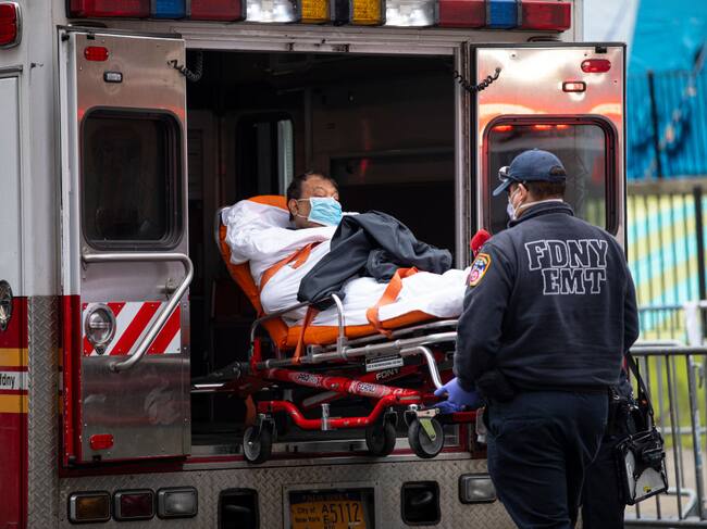 QUEENS, NEW YORK - MARCH 30: Two members of the Fire Department of New York"u2019s Emergency Medical Team wheel in a patient with potentially fatal coronavirus to the Elmhurst Hospital Center in the Queens borough of New York City on March 30, 2020. New York City is the epicenter of the coronavirus pandemic in the United States, putting historic pressure on a world-renowned healthcare system as the number of confirmed cases in the area grows. (Photo by Robert Nickelsberg/Getty Images)