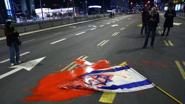 Manifestantes y familias de los rehenes israelíes lanzan una bandera manchada ante el ministerio de defensa de Israel en la ciudad de Tel Aviv