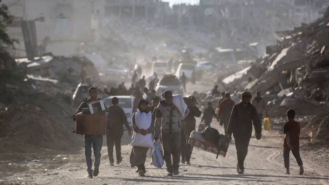 Palestinos desplazados caminan en medio de las ruinas que dejan los ataques militares de Israel sobre la Franja de Gaza en Palestina