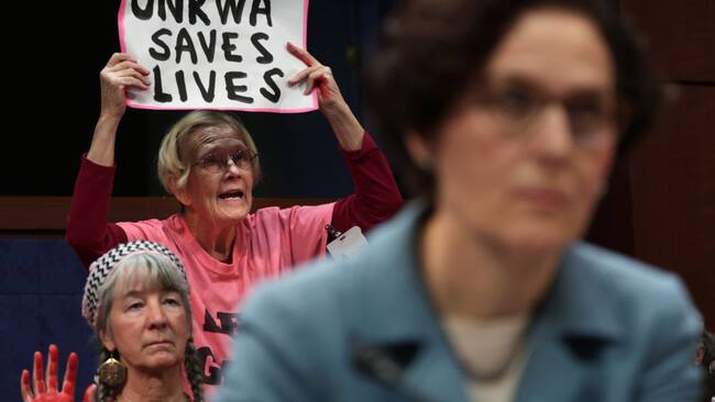 Manifestantes muestran carteles en apoyo a la labor de la UNRWA en Gaza, en una sesión de una comisión de cancillería en el Congreso de Estados Unidos.