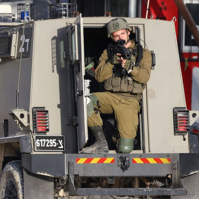 Un soldado de Israel apunta con su arma desde un vehículo blindado, en medio de un operativo en un campo de refugiados en el West Bank de Palestina.