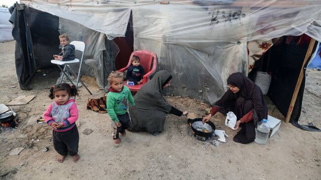Dos mujeres palestinas preparan algo de alimento para darles de comer a cuatro niños en la Franja de Gaza en Palestina.