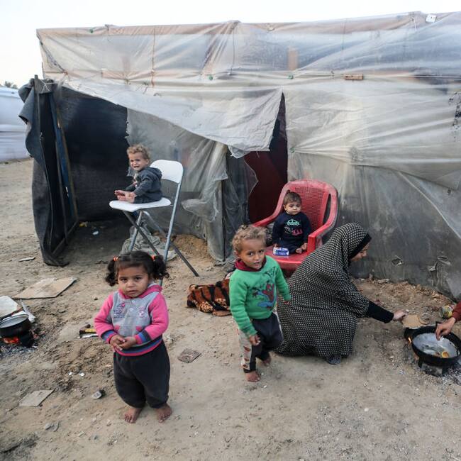 Dos mujeres palestinas preparan algo de alimento para darles de comer a cuatro niños en la Franja de Gaza en Palestina.