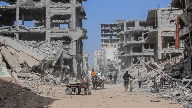 Los desplazados palestinos caminan entre la destrucción que dejan los ataques de Israel contra la Franja de Gaza en Palestina.