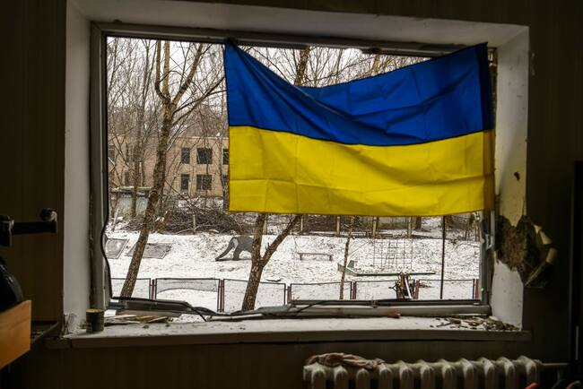 Una bandera de Ucrania cuelga en una ventana de una vivienda destruida en medio de los ataques de Rusia en las cercanías de la capital Kiev.