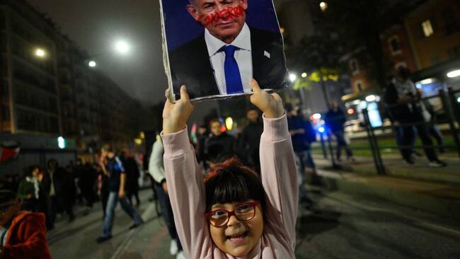 Una niña en Italia porta un cartel que muestra ensangrentado al primer ministro de Israel, Benjamin Netanyahu, por los ataques contra la Franja de Gaza