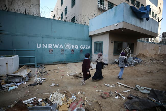 Personas caminan frente a la sede central de la UNRWA en la Franja de Gaza en Palestina.