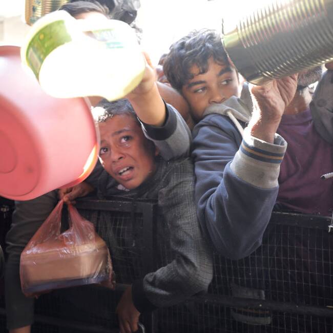 Niños, mujeres y hombres buscan alimentos para colocar en sus inventados plato de comida en la Franja de Gaza en Palestina