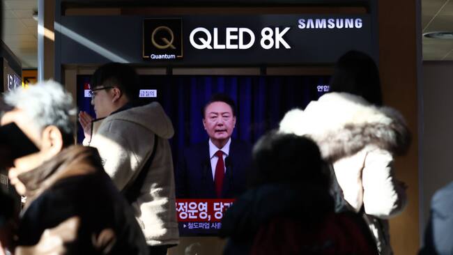 Las personas caminan cerca de un televisor en la ciudad de Seúl donde se muestran noticias del presidente de Corea del Sur, Yoon Suk Yeol