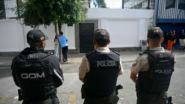 Un grupo de policías de Ecuador vigila desde la calle los accesos a la embajada de México en la ciudad de Quito.