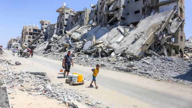 Familias caminan en medio de la destrucción en la Franja de Gaza tras la serie de ataques militares de Israel en contra del territorio de Palestina.